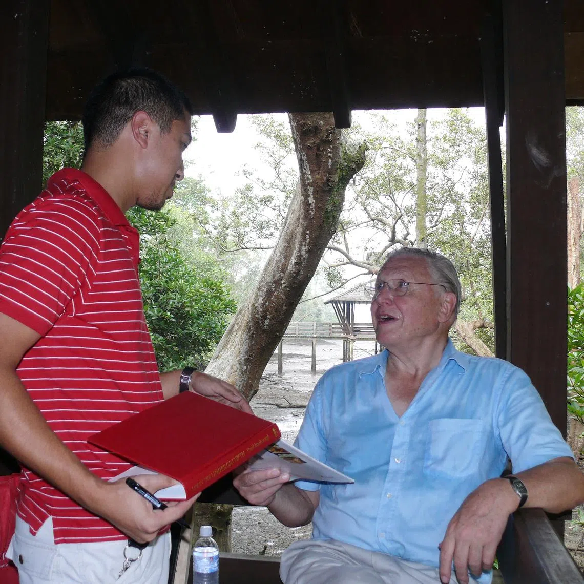 Singaporean Gopalasamy Reuben Clements (left), then an NUS master’s student, presenting Sir David Attenborough with his publication featuring a snail species in 2006.