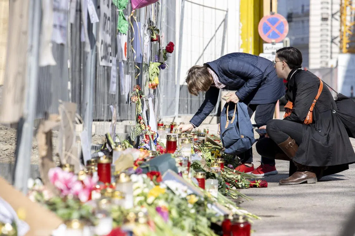 People place flowers and candles at a makeshift memorial in front of the Russian embassy in Vienna, following the death in prison of the Kremlin's most prominent critic, Alexei Navalny. 