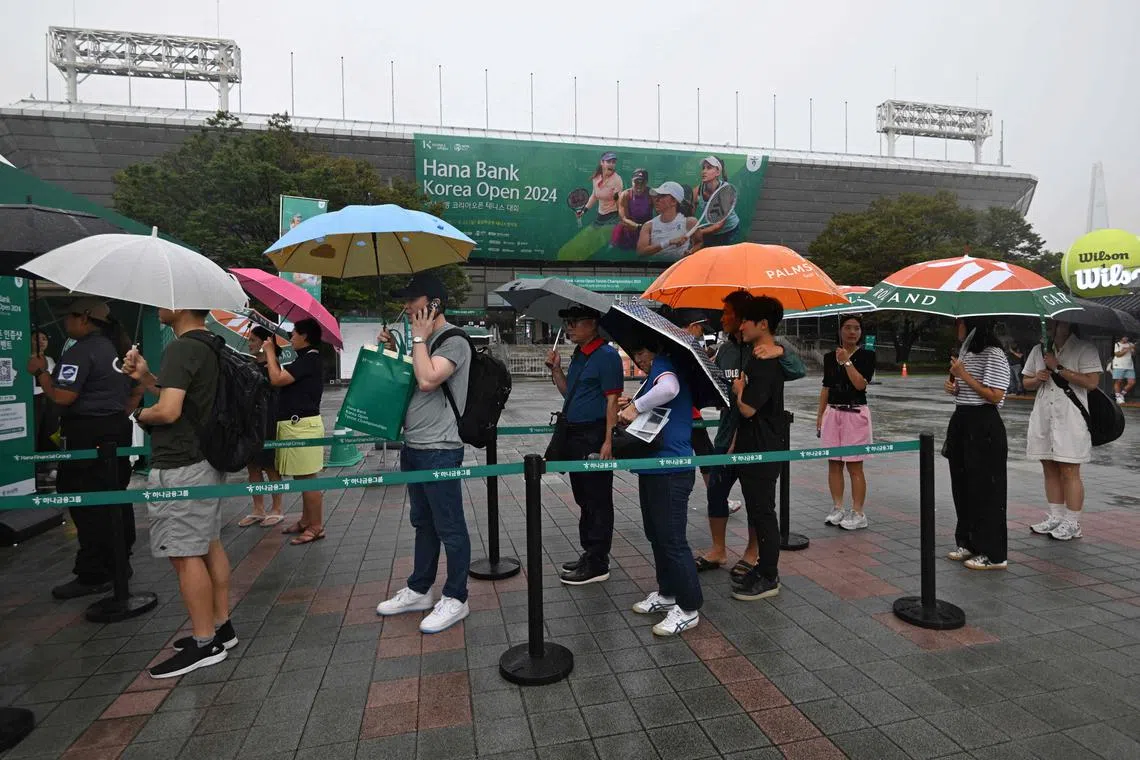 Spectators queueing at an event booth during a rain delay at the Korea Open tennis tournament in Seoul on Sept 20.