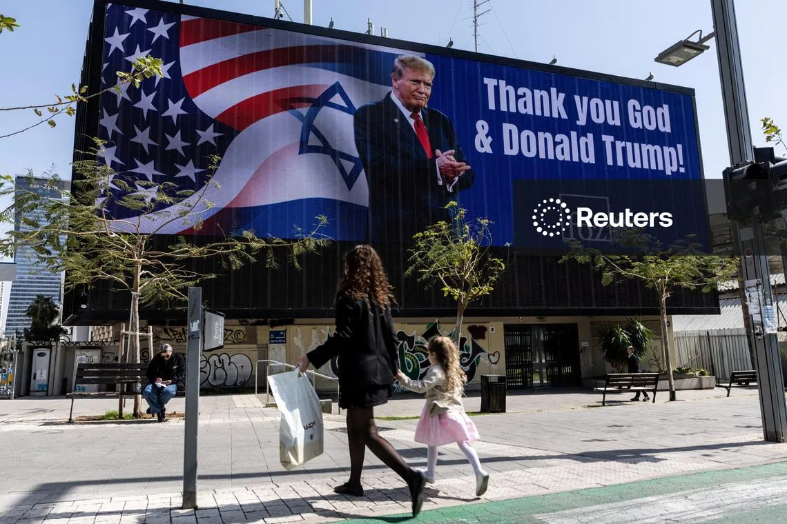 FILE PHOTO: People walk by a billboard commissioned by an evangelical group, which displays a picture of U.S. President Donald Trump with the words \Thank you God & Donald Trump\, amid the U.S.-Israel conflict with Iran, in Tel Aviv, Israel, March 12, 2026. REUTERS/Nir Elias/File Photo