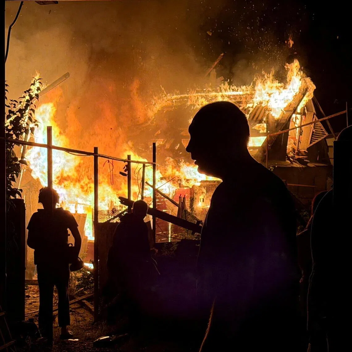 Residents look at a private house that burns after an overnight Russian drone strike in Zaporizhzhia, Ukraine on June 22, 2026.  