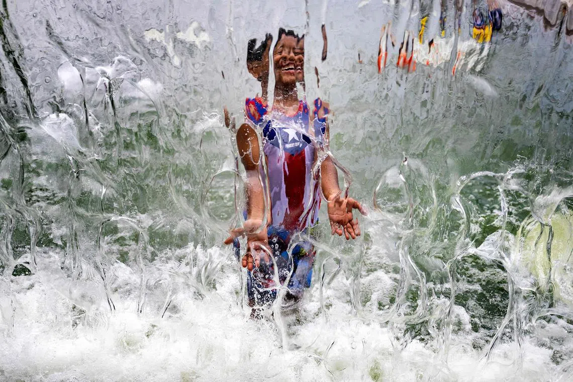 A young boy plays in the water fountain at Yards Park in Washington, DC, on June 26, 2023 as a heatwave settles in on the area. 