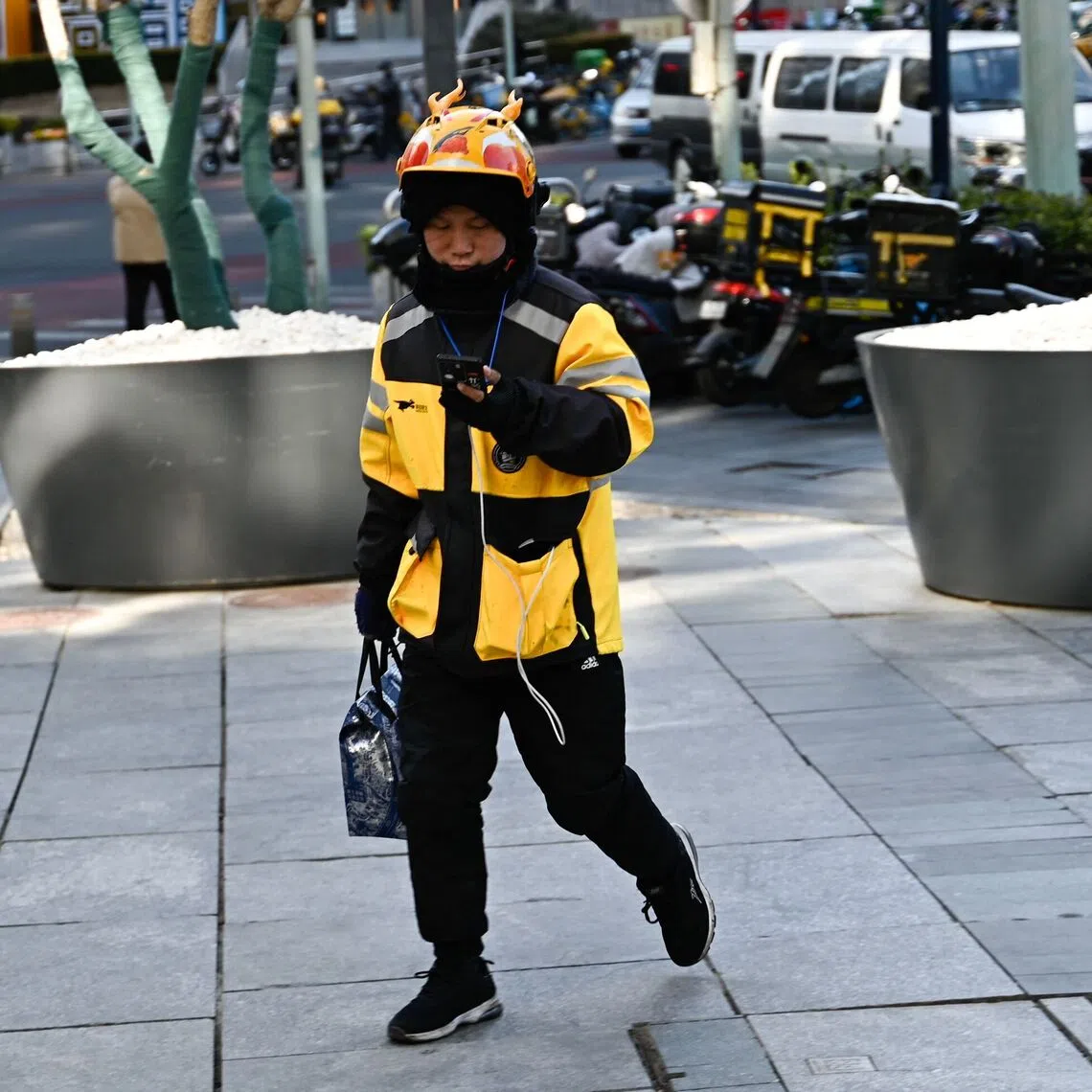 A food delivery man works in Beijing on February 17, 2025. (Photo by Pedro PARDO / AFP)