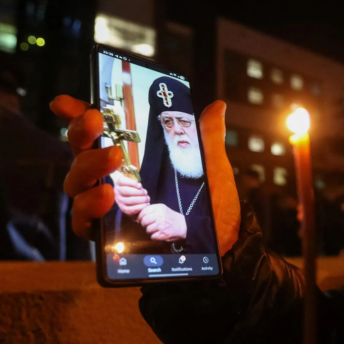A person holds a phone with an image of Georgia's Orthodox Patriarch Ilia II outside the hospital where he was admitted, in Tbilisi, Georgia, March 17, 2026. REUTERS/Irakli Gedenidze