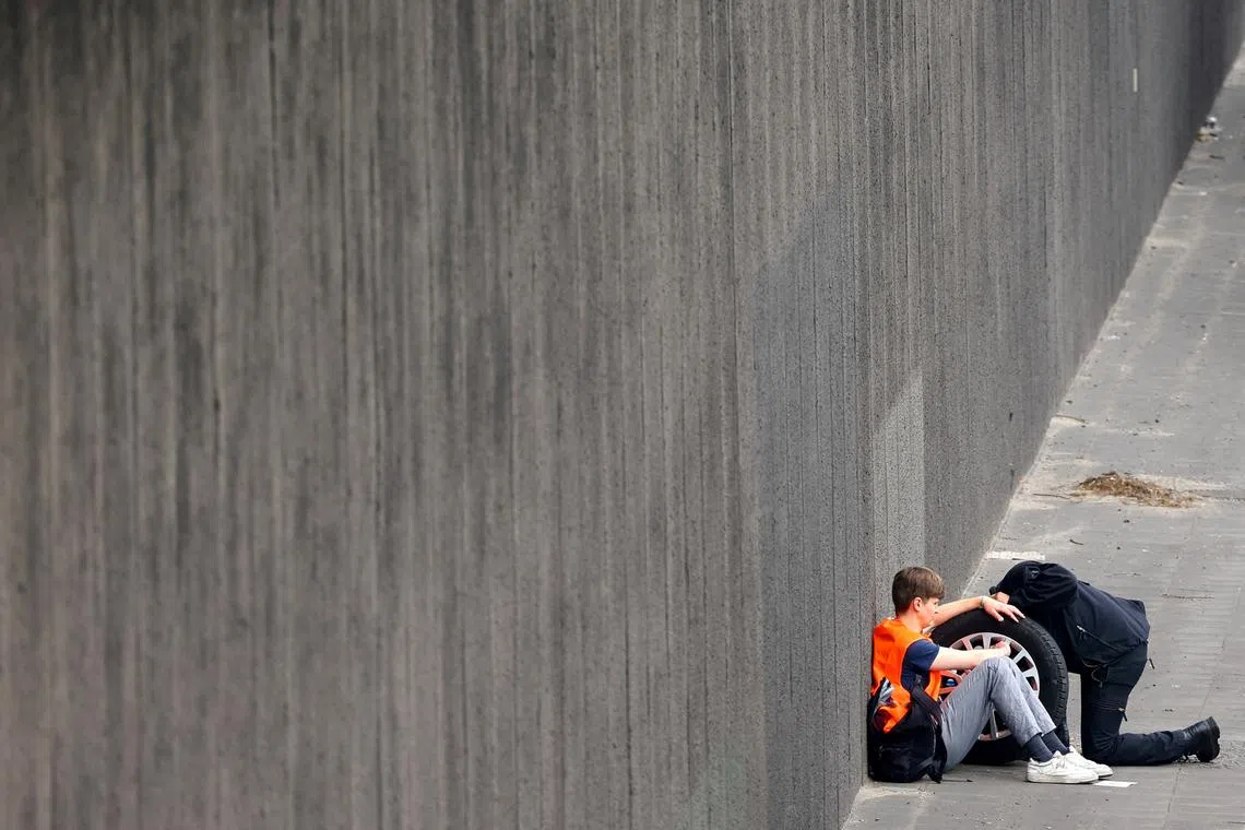 A police man removing glue from a hand of an activist of the "Letzte Generation" (Last Generation)  who previously glued himself to a tire of a car while blocking the central highway A100, to protest for climate councils, a speed limit on highways as well as for affordable public transport, in Berlin, Germany May 15.