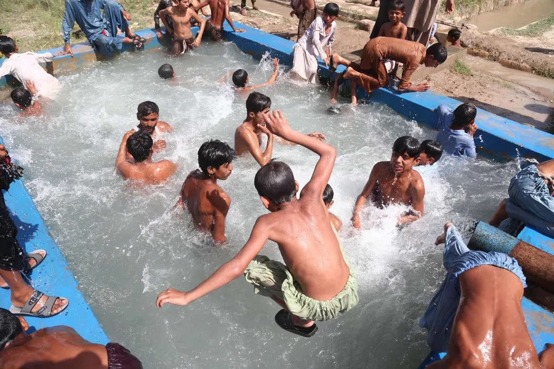 People cool off in a tubewelll to beat the heat in Hala, Pakistan, May 8, 2023. 