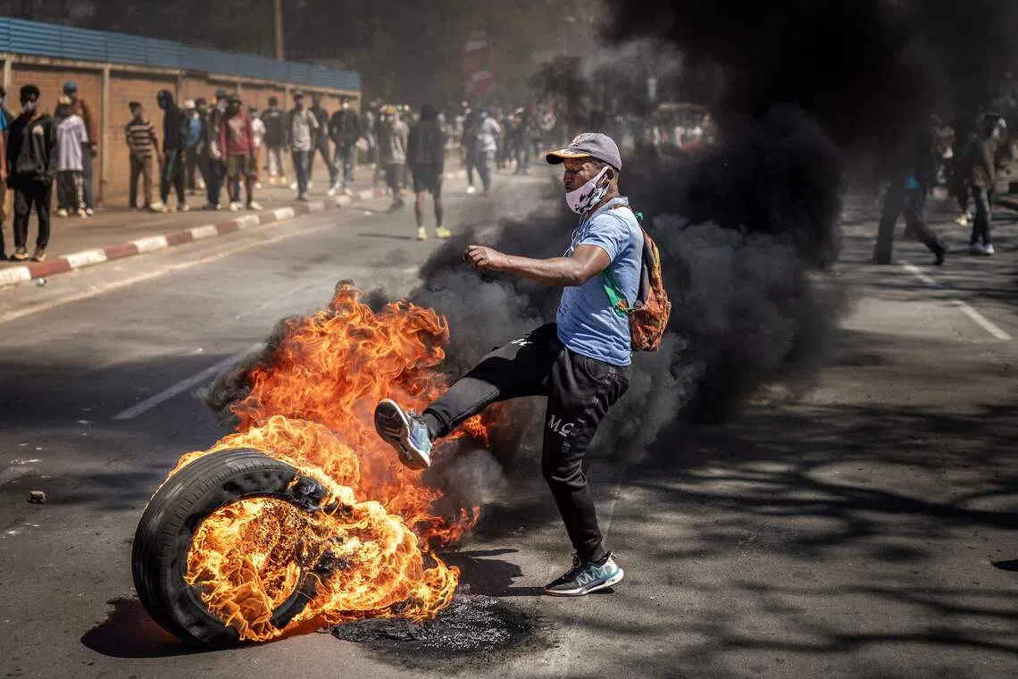 A protester kicking a burning tire amid clashes with Malagasy security forces during a rally calling for constitutional reforms in Antananarivo, on Oct 7, 2025. 