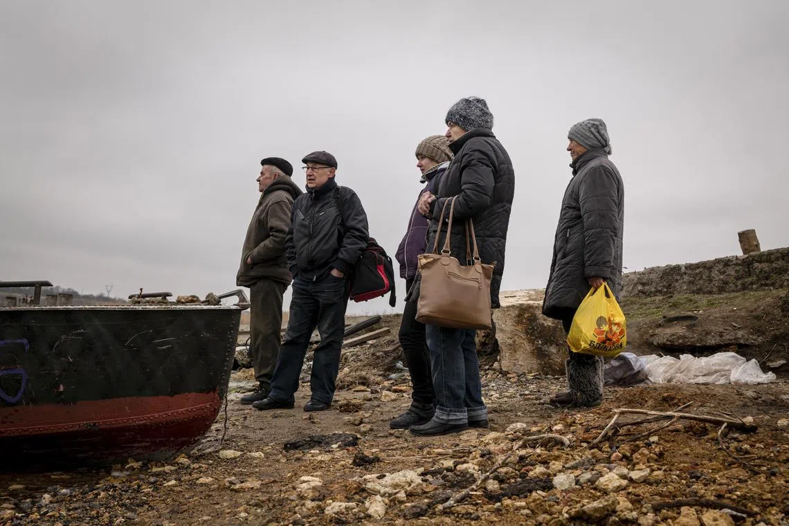 People wait for a rowboat to cross a tributary of the Dnieper River, in the Kherson region of Ukraine on Jan. 24, 2023. Carving an arc through Ukraine from its northern border to the Black Sea, through Kyiv, Zaporizhzhia and Kherson, the Dnieper shapes the countryÕs geography and economy, its culture and its very identity. (Nicole Tung/The New York Times)
