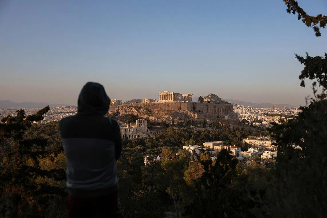 A man looks at the Acropolis and the cityscape in Athens, Greece, April 12, 2024. REUTERS/Louisa Gouliamaki