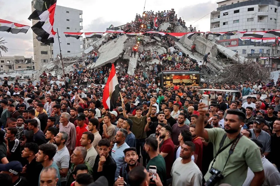 TOPSHOT - Displaced Palestinians watch the 2026 World Cup Round of 16 match between Egypt and Argentina on a giant screen as they sit on the rubble of destroyed buildings in Gaza City on July 7, 2026. (Photo by Omar AL-QATTAA / AFP)