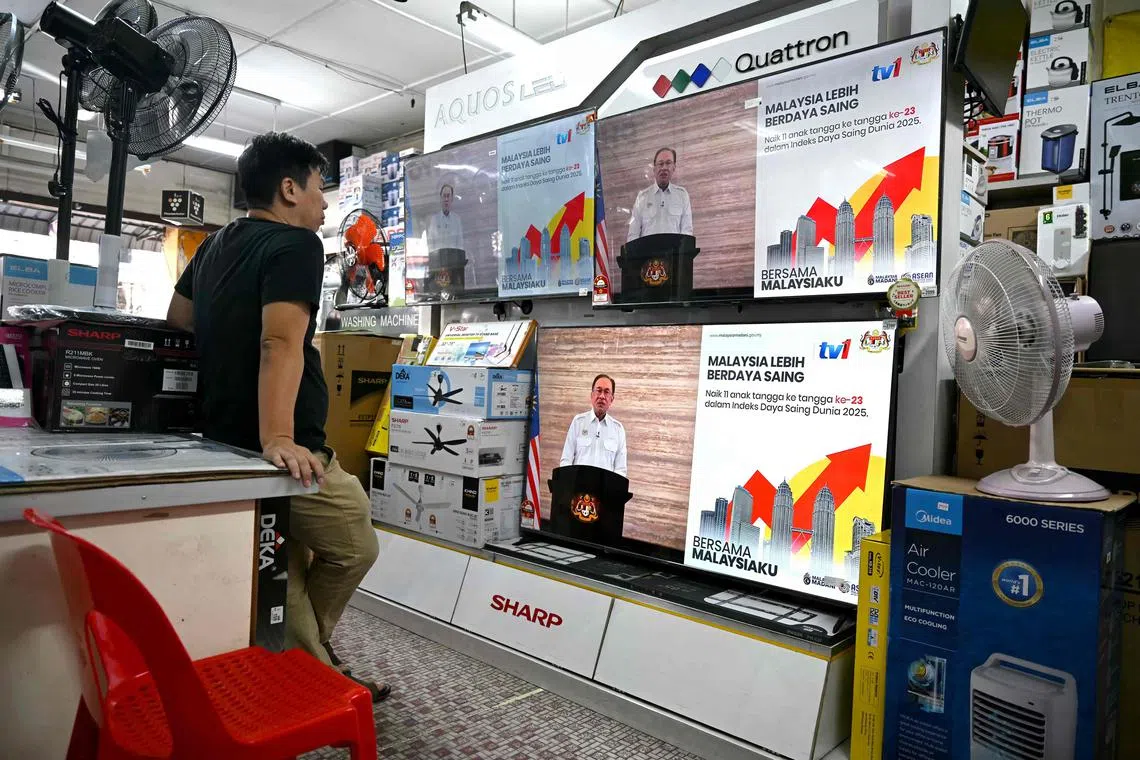 A store clerk watches as Prime Minister Anwar Ibrahim addresses Malaysians during a live telecast on July 23, 2025.