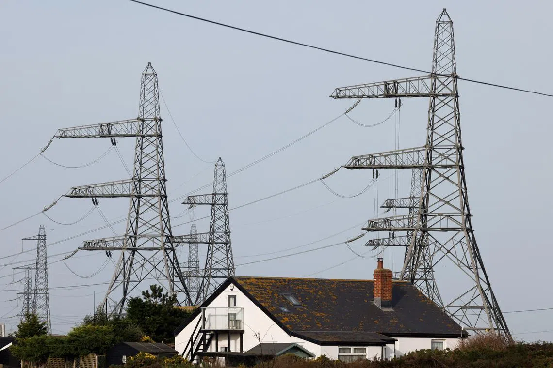 FILE PHOTO: Electricity pylons are seen behind a local house in Dungeness, Britain, October 8, 2023. REUTERS/Carlos Jasso/File Photo