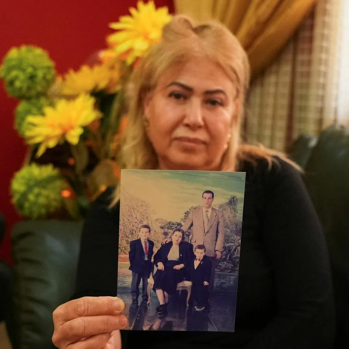 Sofia Ben Agla, wife of detained opposition leader Ghazi Chaouachi, poses for the camera while holding an old photo of herself, her husband, and their two sons inside her home in Tunis, Tunisia, on February 26, 2026. REUTERS/Stringer