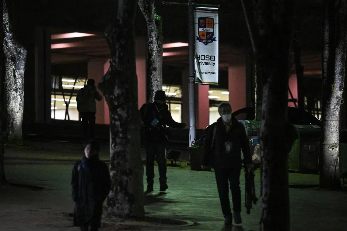 People walk past a banner (C-top) for Hosei University near the entrance to the university's Tama campus after a woman brandished a hammer inside a classroom, in Machida in the western suburbs of Tokyo on January 10, 2025. Eight people were wounded in a hammer attack at a university in Tokyo on January 10, with a 22-year-old student arrested at the scene, Japanese media said. (Photo by Philip FONG / AFP)
