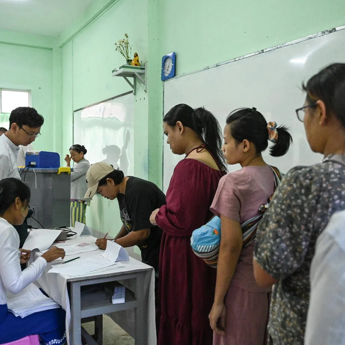 People line up to vote inside a polling station during the first phase of Myanmar's general election in Yangon on Dec 28, 2025.  