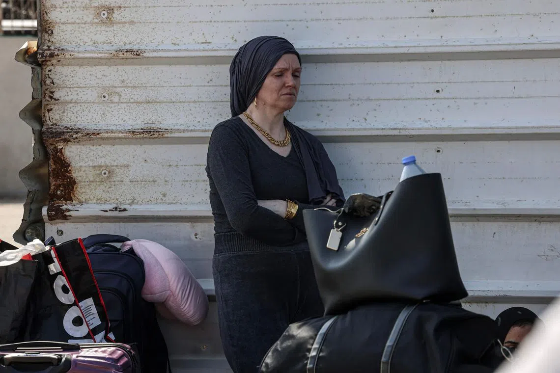 A Palestinian woman with a foreign passport waits at the Rafah gate hoping to cross into Egypt as Israel's attacks on the Gaza Strip continues on October 14, 2023. International aid groups and major powers have pleaded with Israel to set up safe zones in Gaza where thousands struggled on October 14 to get out of a major part of the Palestinian territory under threat of attack. (Photo by SAID KHATIB / AFP)