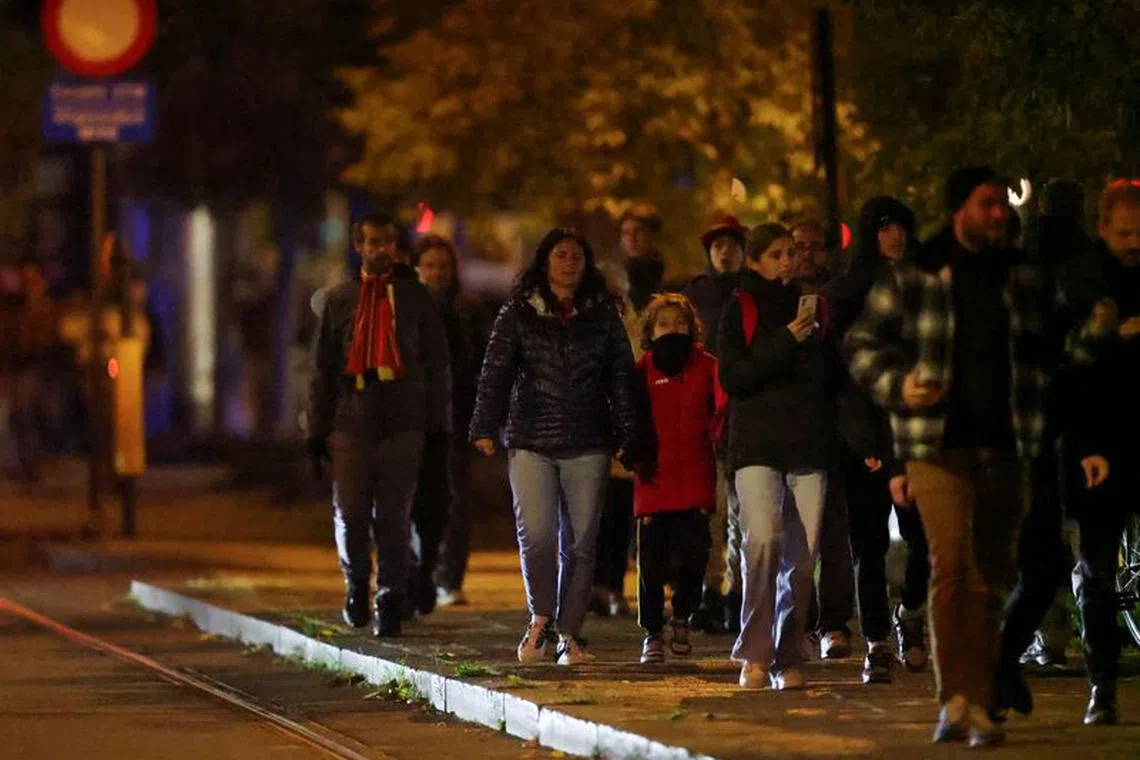 People walk outside King Baudouin Stadium after the match between Belgium and Sweden was suspended following a shooting in Brussels.