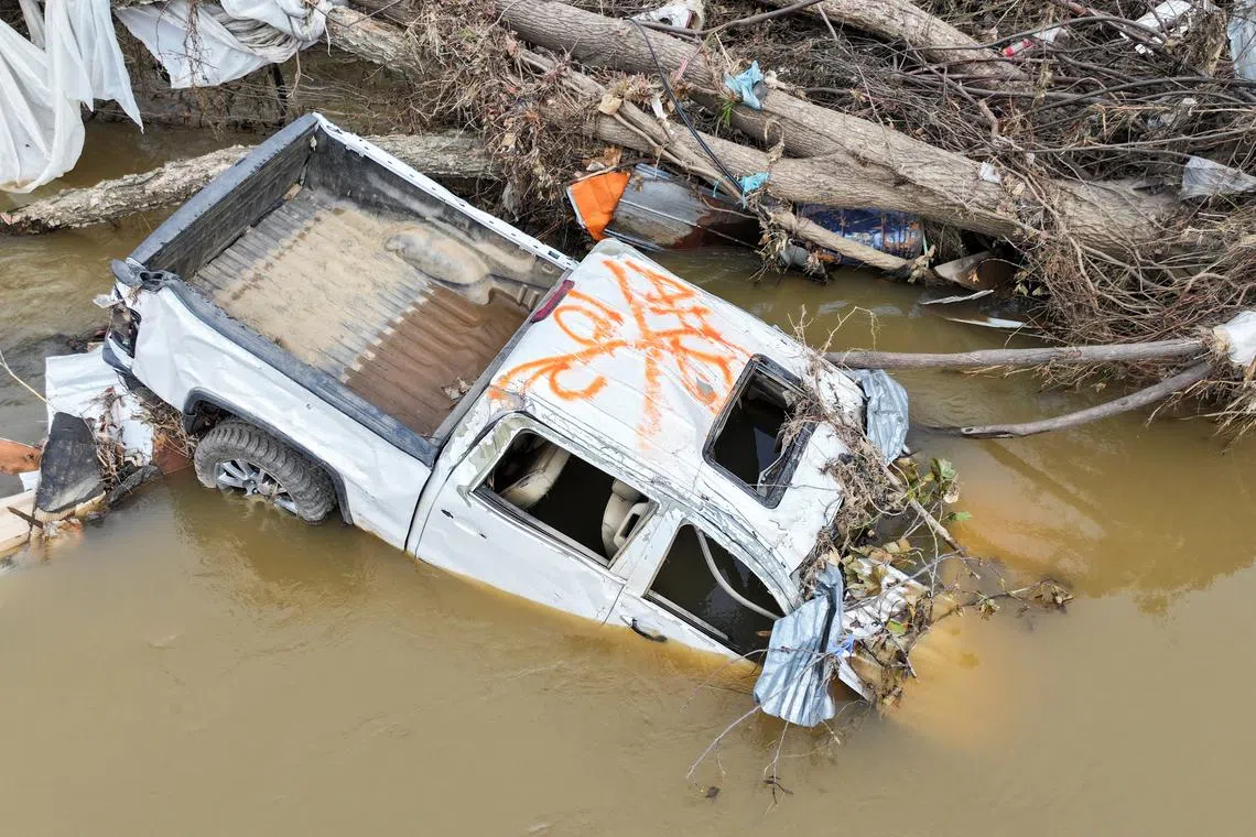 A drone view shows a pick-up truck partially submerged in the Swannanoa River near Biltmore Village, after Hurricane Helene hit the area.