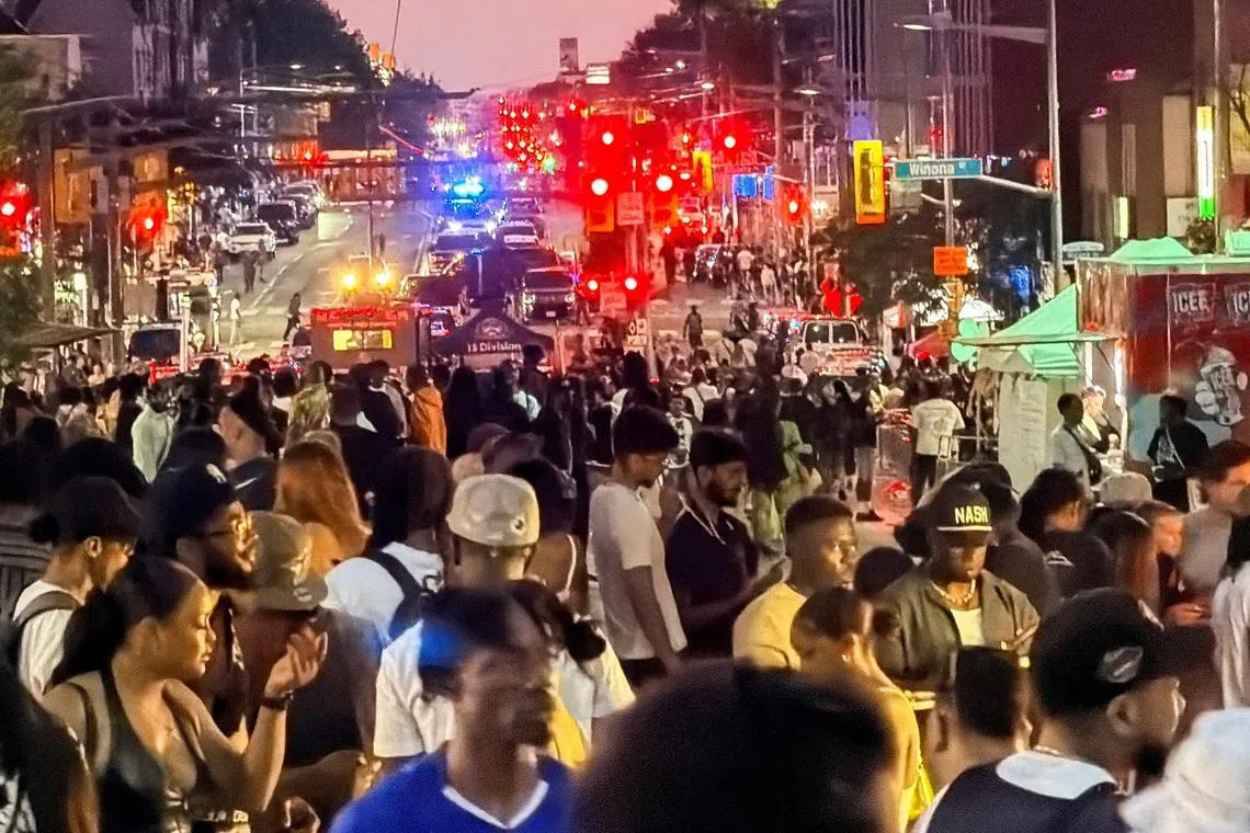 People gather as emergency workers respond at the scene after a deadly shooting, at a salsa-themed street festival in Toronto on July 11.