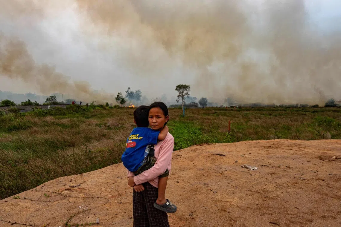 Poppy, 12, was carrying her brother as Indonesian firefighters try to extinguish a peatland fire near her house in South Sumatra on Oct 4. 