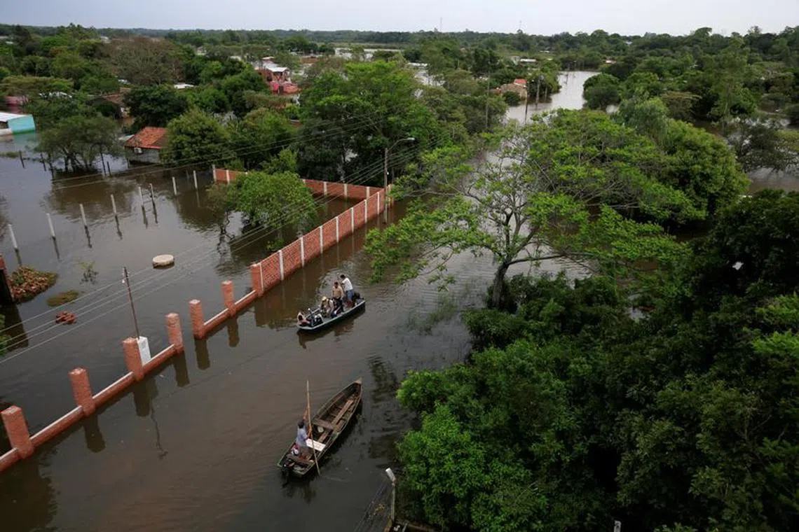 People ride in boats in a flooded area after the Parana river overflowed its banks due to heavy rain upstream, in Ayolas, Paraguay November 8, 2023. REUTERS/Cesar Olmedo