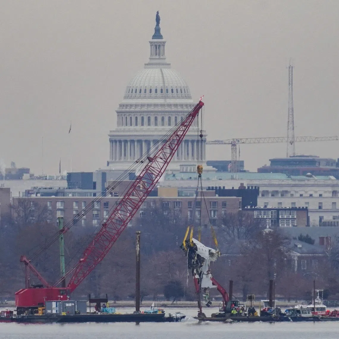 A crane retrieves part of the wreckage from the Potomac River, in the aftermath of the collision of American Eagle flight 5342 and a Black Hawk helicopter that crashed into the river, with the Capitol dome in the background, as seen from Virginia, U.S., February 3, 2025.REUTERS/Nathan Howard/File Photo