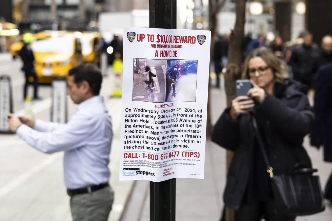 epa11757509 People look at a 'Wanted' poster put up by the New York City police department outside of the New York Hilton hotel near the scene where UnitedHealthcare’s CEO Brian Thompson was shot and killed in an apparent targeted attack as he was en-route to attend UnitedHealthcare’s annual investor conference this morning in New York, New York, USA, 04 December 2024. The masked gunman is still being sought following the early morning shooting in Manhattan after fleeing towards Central Park.  EPA-EFE/JUSTIN LANE