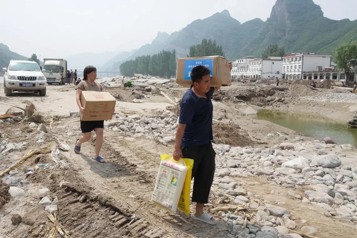 epa10793306 Villagers carrying disaster relief rice walk back home in Shangzhuang Village of Sanpo Town, Laishui County, north China's Hebei Province, 09 August 2023 (issued 10 August 2023). Affected by heavy rainfall, some villages in Laishui County encountered traffic and communication disruptions. Local authorities have made every effort in mending infrastructure damaged by flood while delivering disaster relief supplies purchased by the government and donated by all walks of life to flood-affected residents.  EPA-EFE/XINHUA / Yang Shiyao CHINA OUT / MANDATORY CREDIT  EDITORIAL USE ONLY