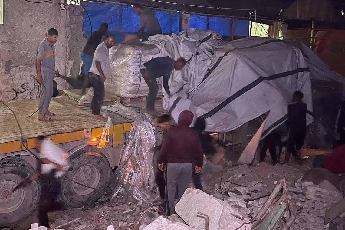 Palestinian workers unloading sacks of flour from an aid truck at a bakery, in Khan Younis on May 21. 