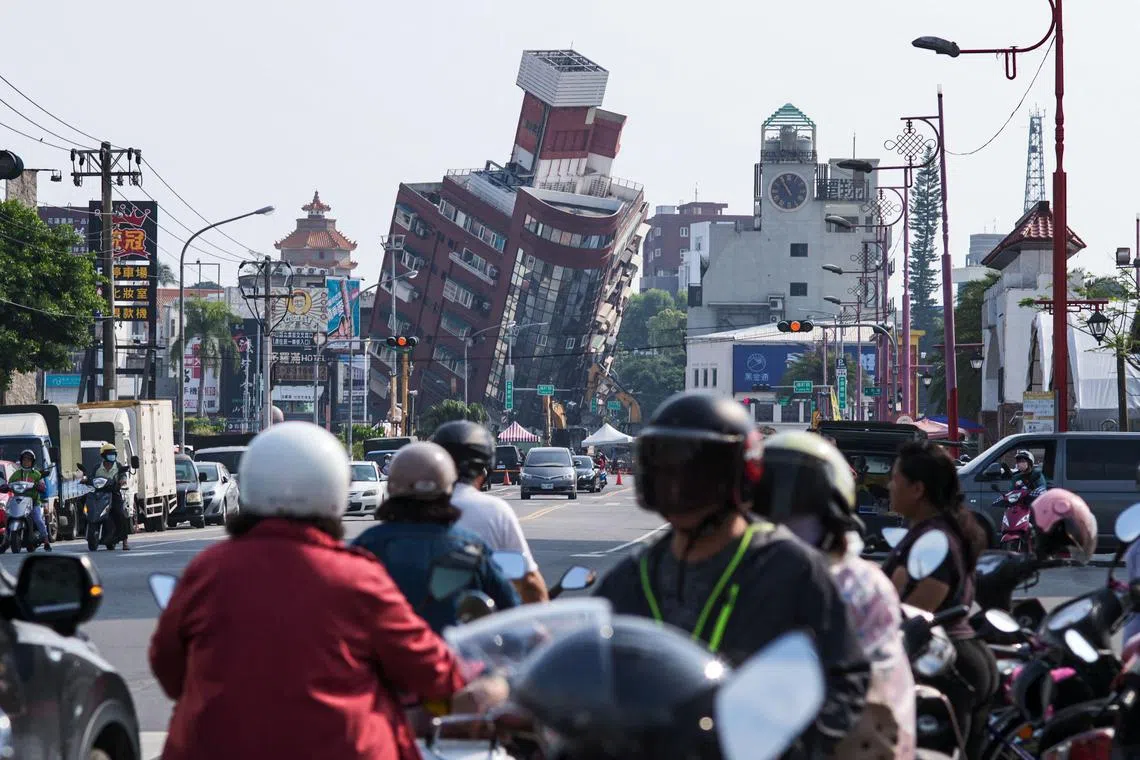 TOPSHOT - Local residents ride past a damage of building caused by the earthquake in Hualien on April 4, 2024. At least nine people were killed and more than 1,000 injured by a powerful earthquake in Taiwan that damaged dozens of buildings and prompted tsunami warnings as far as Japan and the Philippines before being lifted. (Photo by Sam Yeh / AFP)