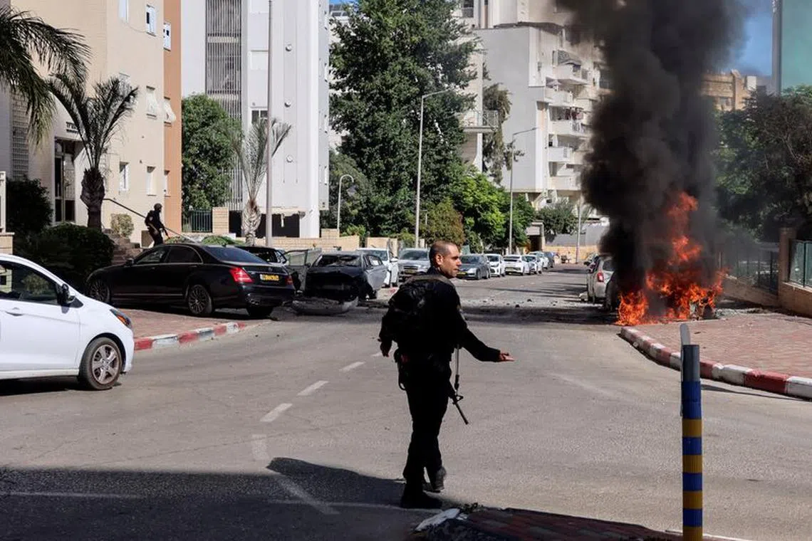 A member of Israel&#039;s police forces walks towards a fire as rockets are launched from the Gaza Strip, in Ashkelon, southern Israel October 7, 2023. REUTERS/Sinan Abu Mayzer