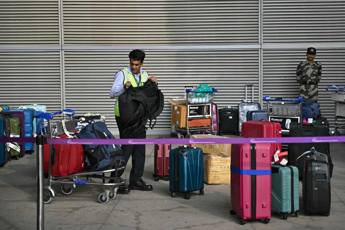 A ground staff member sorts luggage of stranded passengers at the baggage collection area of Kempegowda International Airport in Bengaluru on Dec 6.