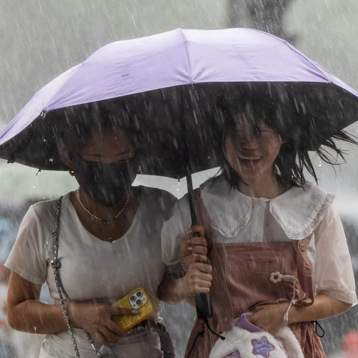 Two women carrying an umbrella walk under heavy rain in Beijing, China, on July 10.
