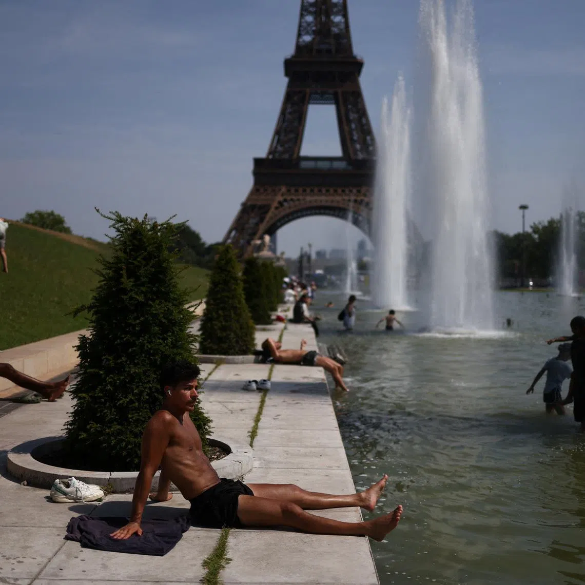 A person sunbathes next to the Trocadero Fountains by the Eiffel Tower during high temperatures amid a heatwave in Paris, France, June 27, 2026. REUTERS/Tom Nicholson