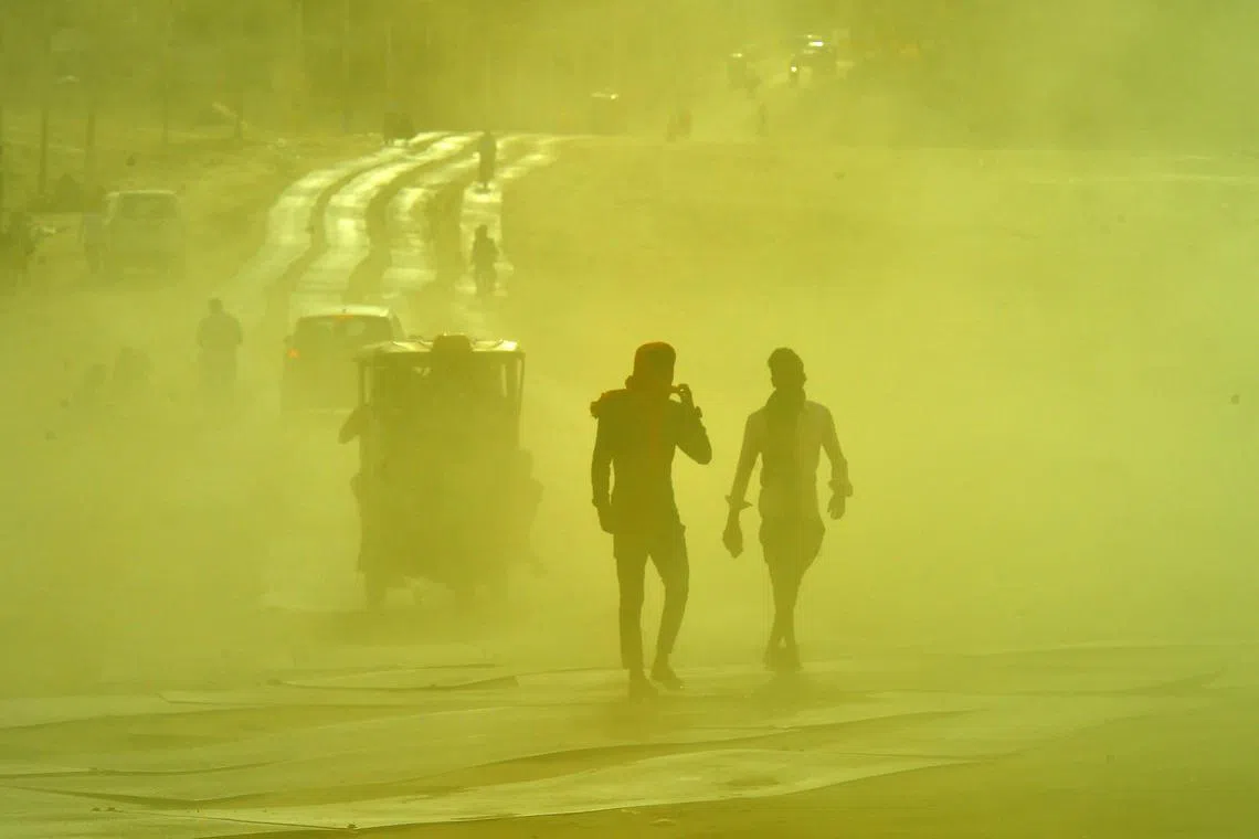 People commute along a road during a sand storm at the Sangam, the confluence of the rivers Ganges, Yamuna and mythical Saraswati on a hot summer day in Prayagraj on June 13, 2023.