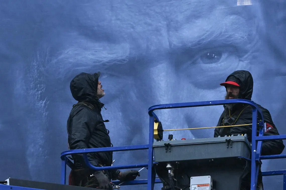 Workers on an aerial lift installing a new banner featuring US President Donald Trump on the façade of the US Department of Justice headquarters, in Washington, DC, on Feb 19, 2026.