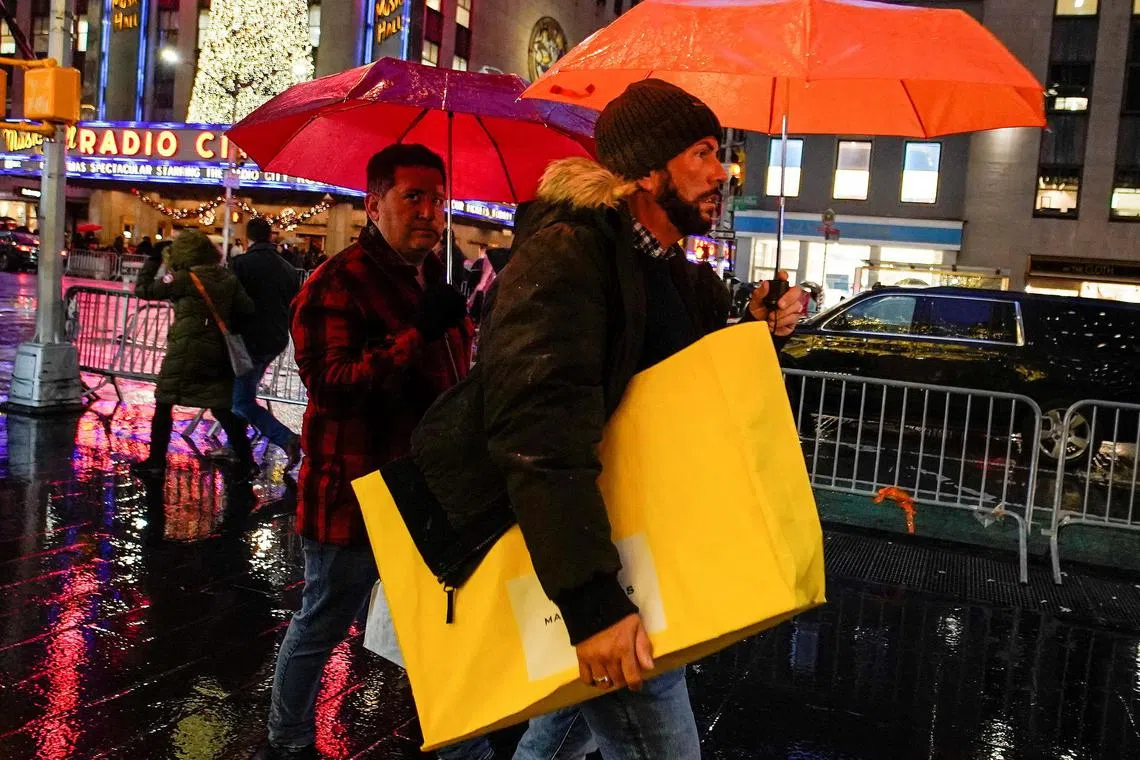 A man walks under the rain with his shopping bag during the holiday season in New York City, U.S., December 15, 2022. REUTERS/Eduardo Munoz/File Photo