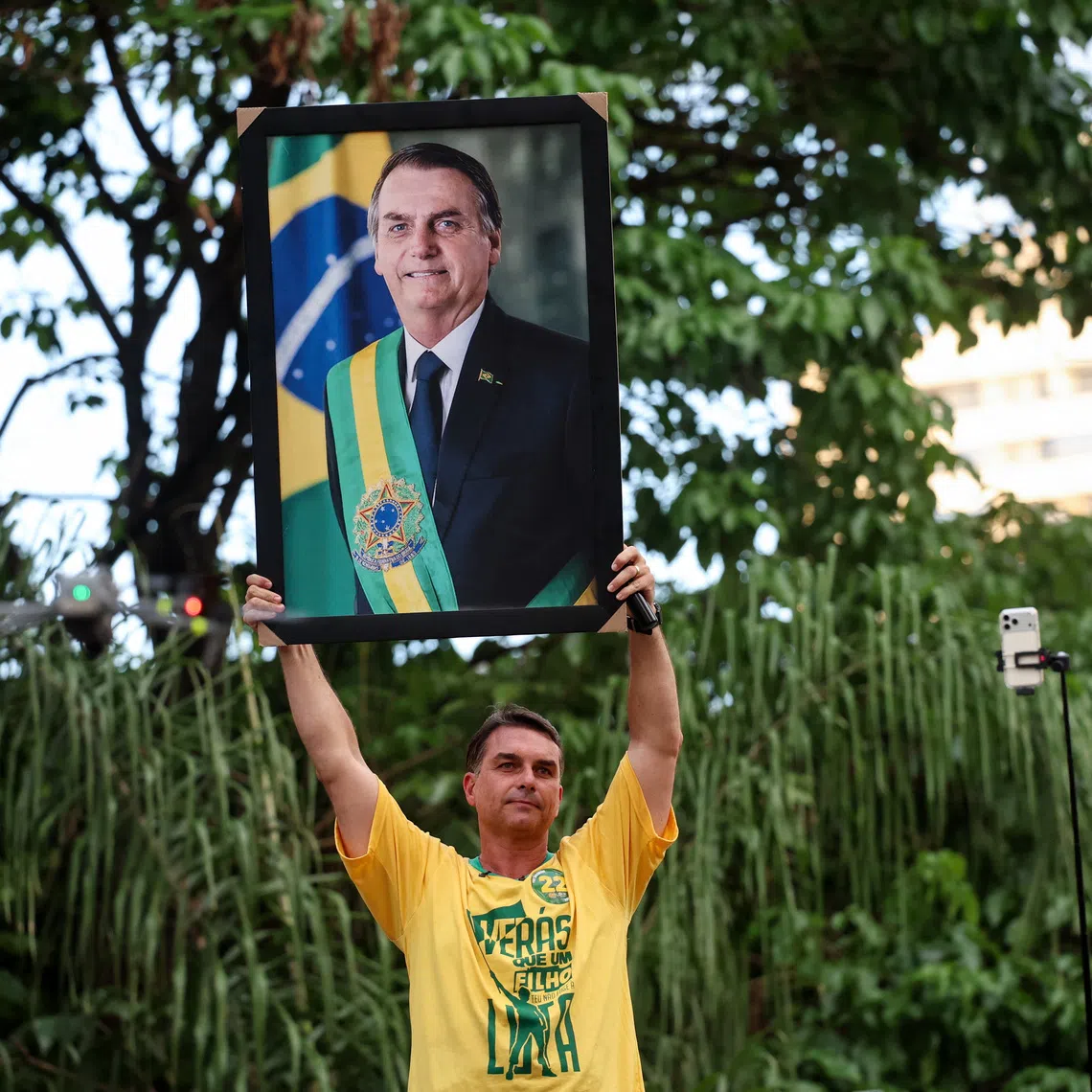 Brazilian presidential candidate Flavio Bolsonaro of the Liberal Party (PL) holds up a portrait of his father, Brazil's former President Jair Bolsonaro, during a campaign rally in Goiania, Brazil, September 27, 2026. REUTERS/Adriano Machado