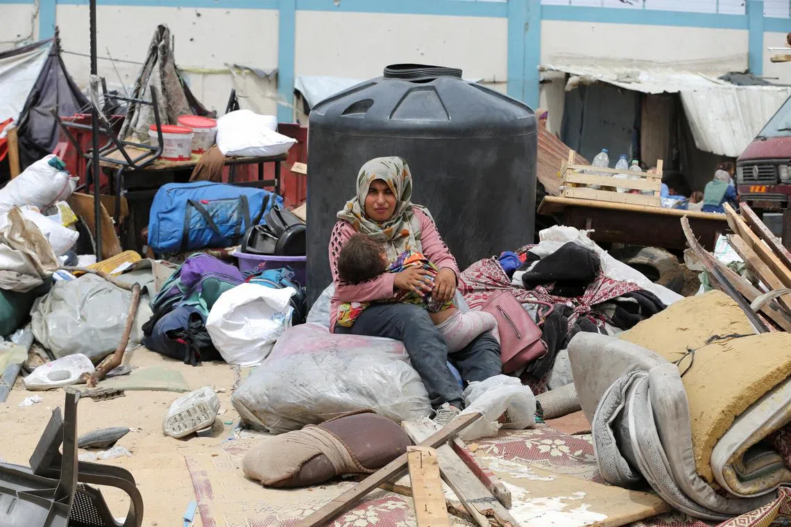 A woman sits with a child, on the day Palestinians travel on foot as they flee Rafah due to an Israeli military operation, on May 28.