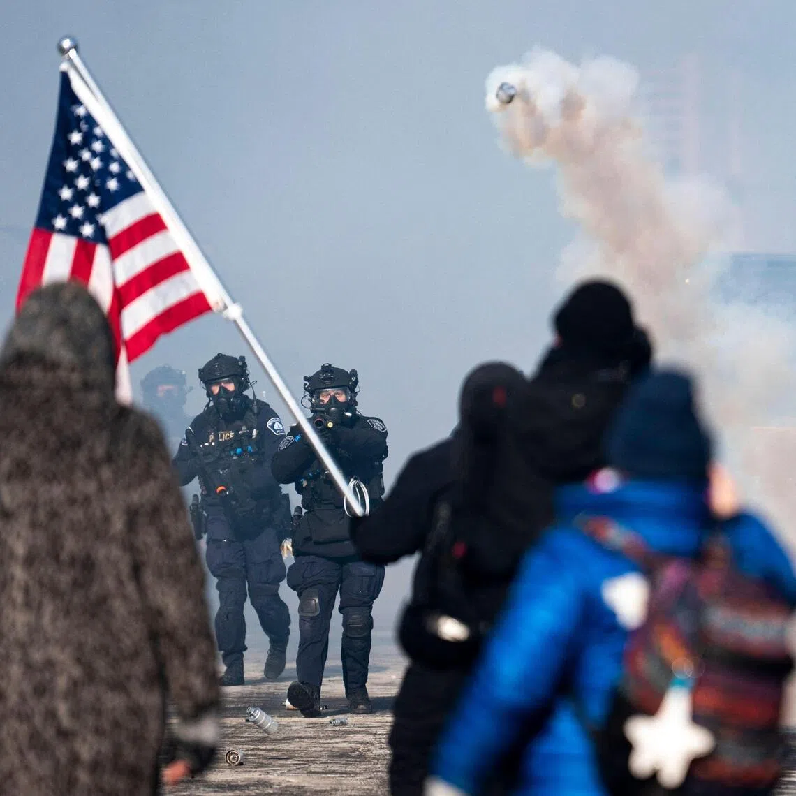 A Minneapolis police officer throwing a can of tear gas at people gathered on Nicollet Avenue following a fatal shooting by federal agents.