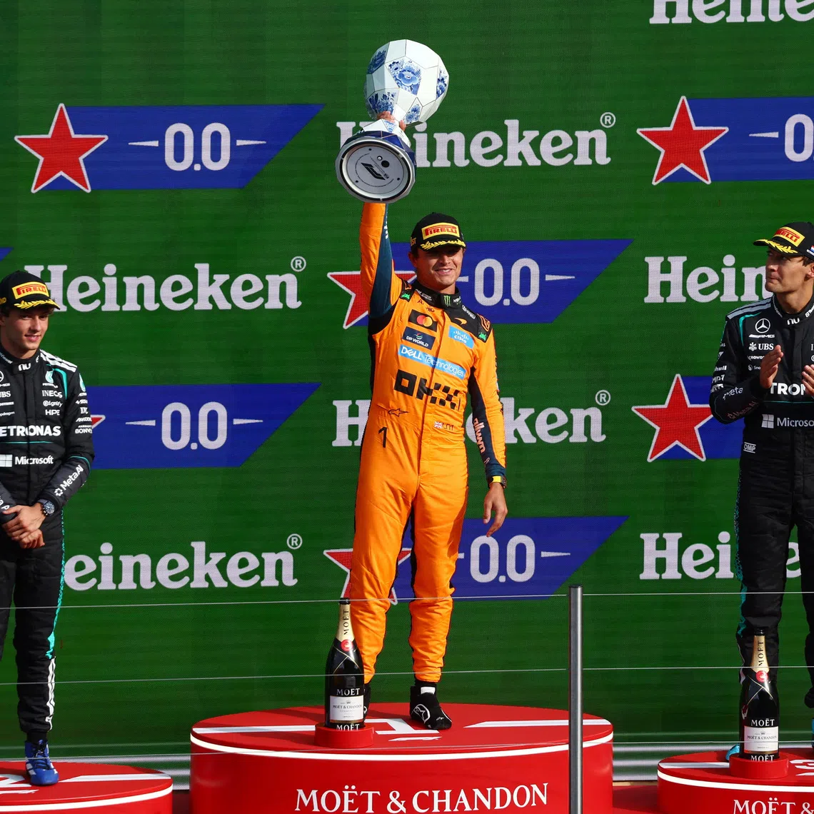 Formula One F1 - Dutch Grand Prix - Circuit Zandvoort, Zandvoort, Netherlands - August 23, 2026 McLaren's Lando Norris celebrates on the podium with the trophy after winning the Dutch Grand Prix alongside second placed Mercedes' Andrea Kimi Antonelli and third placed Mercedes' George Russell REUTERS/Jakub Porzycki
