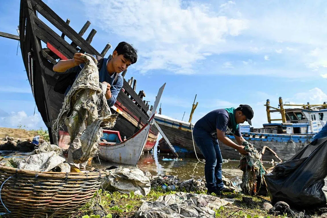 TOPSHOT - University students clean up plastics and other debris washed ashore at a port in Banda Aceh on May 21, 2023. (Photo by CHAIDEER MAHYUDDIN / AFP)
