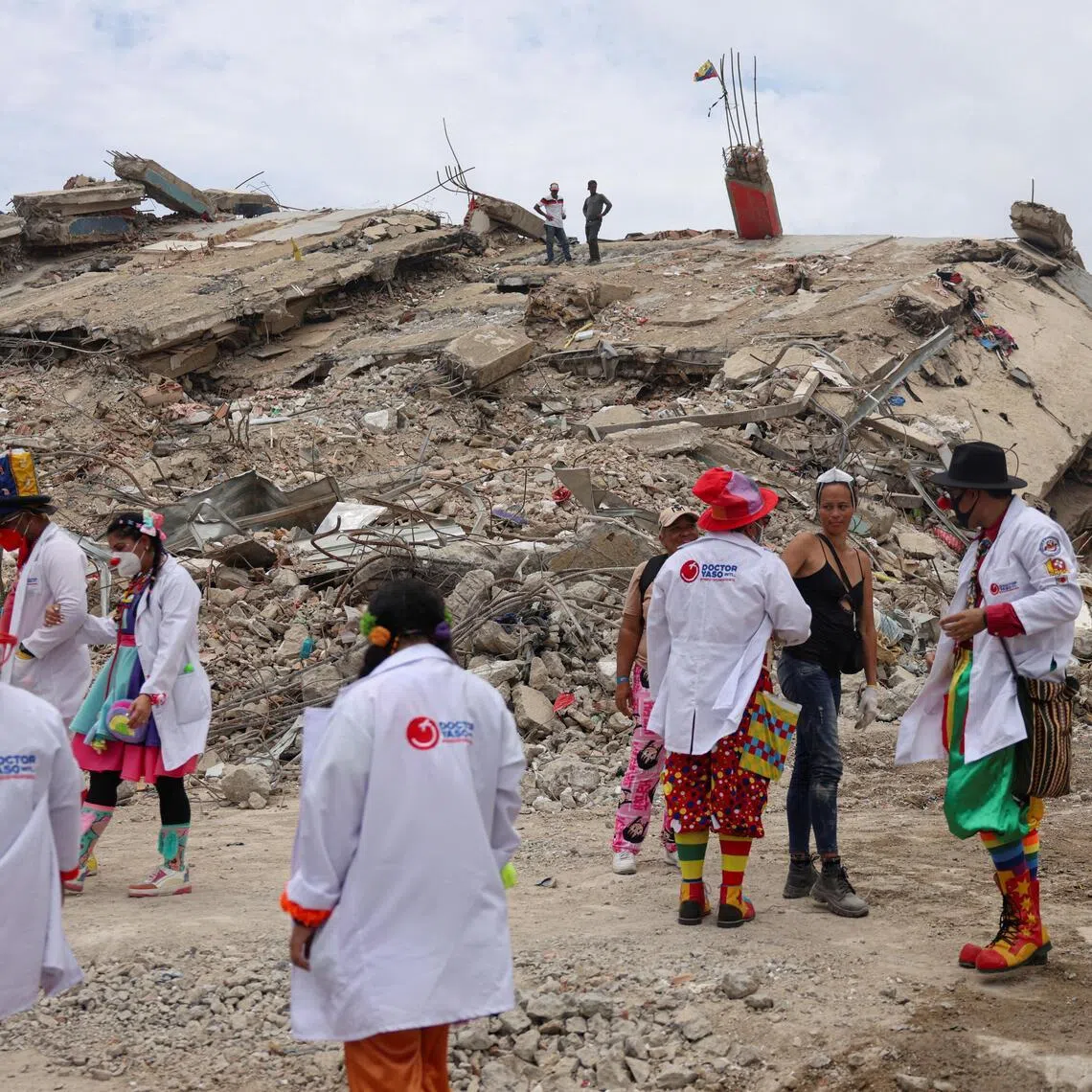 Members of the Venezuelan NGO ‘Doctor Yaso, Payasos de Hospital’ dressed in clown costumes, comfort residents as people search for their loved ones beneath the rubble in La Guaira on July 18.