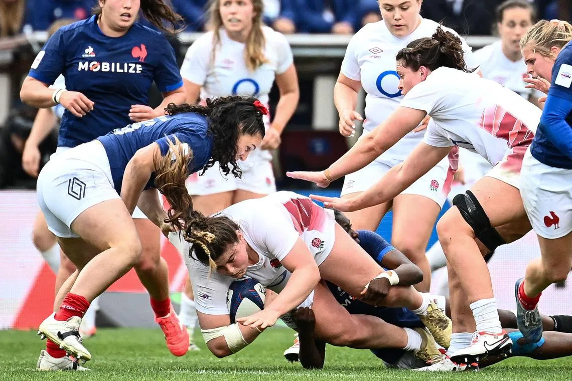 England's prop Maud Muir (C) is tackled during the Six Nations international women's rugby union match between France and England at Chaban-Delmas Stadium in Bordeaux, on April 27, 2024. 