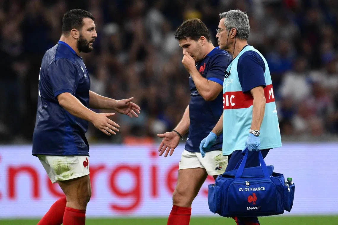 France prop Dorian Aldegheri offers a hand of support to scrum-half and captain Antoine Dupont as he leaves the field with the medic after suffering a facial injury.