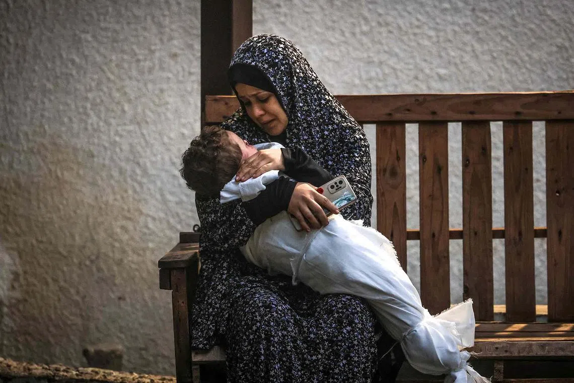 A woman from the Palestinian Ashour family holding the body of a baby who was killed in Israeli bombardment, on Dec 14, 2023, at Najar hospital in Rafah, in the southern Gaza Strip, amid ongoing battles between Israel and the Palestinian militant group Hamas. 