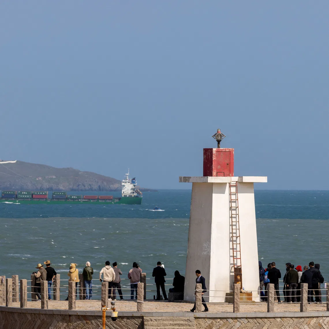 People look across the strait from a lighthouse at the 68-nautical-mile scenic spot, one of mainland China's closest points to the island of Taiwan, on Pingtan Island, Fujian province, China, April 9, 2023. REUTERS/Thomas Peter