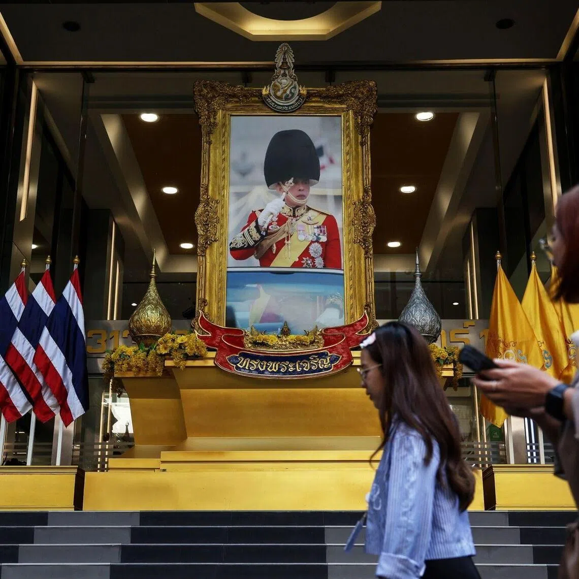Pedestrians walk past a portrait of Thailand's King Maha Vajiralongkorn in Bangkok.