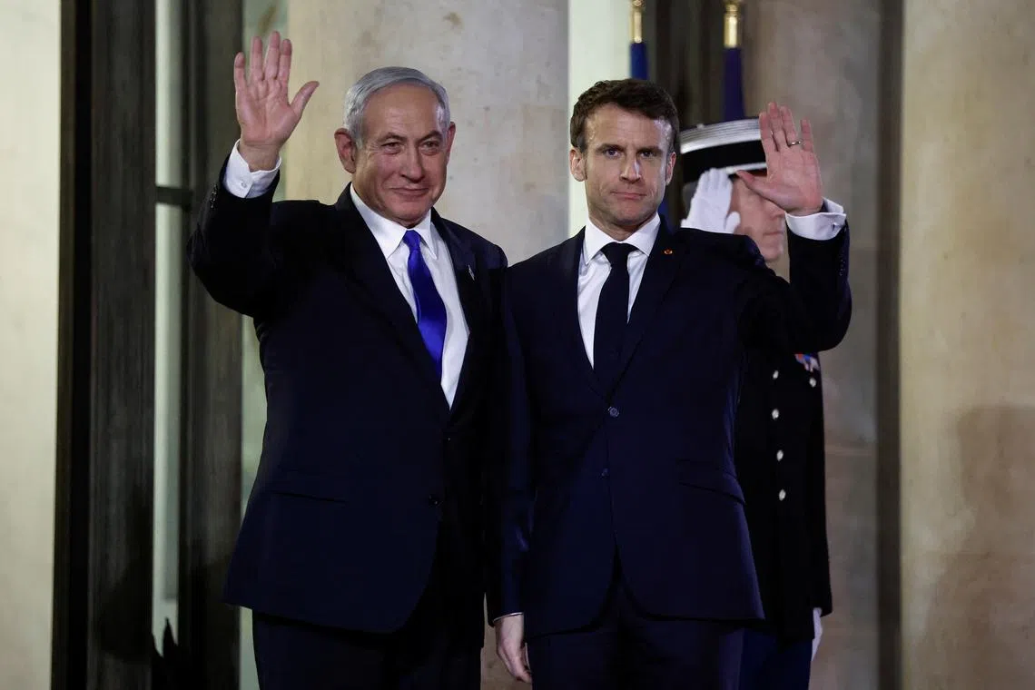 FILE PHOTO: French President Emmanuel Macron and Israeli Prime Minister Benjamin Netanyahu wave as Netanyahu arrives for a dinner at the Elysee Palace, in Paris, France, February 2, 2023. REUTERS/Benoit Tessier/File Photo
