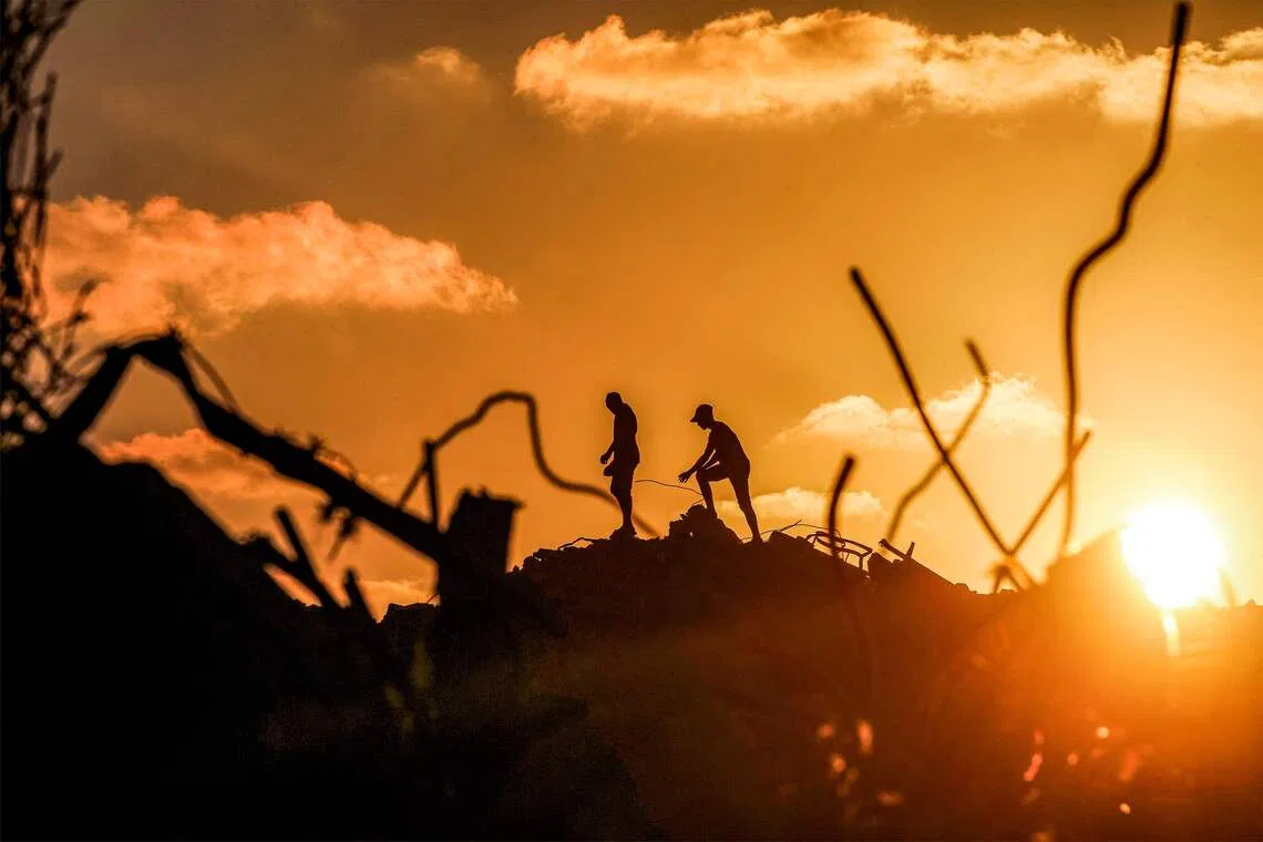 TOPSHOT - Men walk through rubble at the Bureij camp for Palestinian refugees in the central Gaza Strip on September 14, 2026. (Photo by EYAD BABA / AFP)